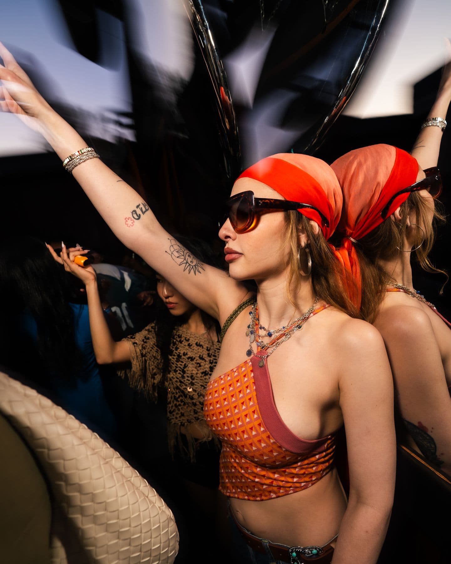 A dancer in an orange headscarf, arms up